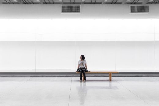 Una mujer sentada en un banco en una habitación grande sin muebles, Guilherme Stecanella, unsplash.com